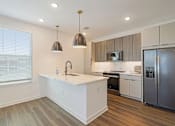 Thumbnail 75 of 124 - Modern kitchen with white island and wood tone cabinets at Velara Luxury Apartments, Ponte Vedra Beach, Florida