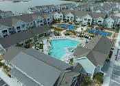 Thumbnail 17 of 62 - A large swimming pool is surrounded by a covered patio and a building.