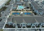 Thumbnail 15 of 62 - An aerial view of a residential complex with a pool and a parking lot.
