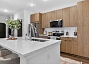Thumbnail 7 of 44 - A modern kitchen with wooden cabinets and a white countertop.at The Logan Luxury Apartments, Nampa, ID, 83651