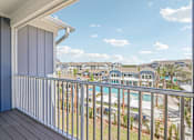 Thumbnail 82 of 124 - Covered balcony overlooking community pool and buildings at Velara Luxury Apartments, Ponte Vedra Beach, Florida