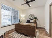 Thumbnail 34 of 58 - an office with a large window and a wooden desk and a ceiling fan at Meridian at CityPlace, Woodbury, MN