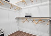 Thumbnail 9 of 24 - A white wall with a shelf and hangers on it.