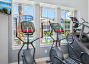 Thumbnail 110 of 124 - Fitness center with cardio equipment and pool views at Velara Luxury Apartments, Ponte Vedra Beach, FL 32081