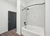 Thumbnail 59 of 60 - A white bathroom with a black door and a white tub.
