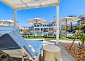 Thumbnail 105 of 124 - Poolside cabana with lounger and umbrella seating at Velara Luxury Apartments, Florida