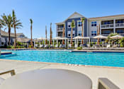 Thumbnail 21 of 124 - Swimming pool with cabanas palm trees and apartment buildings at Velara Luxury Apartments, Ponte Vedra Beach