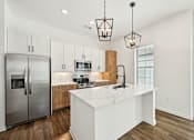Thumbnail 19 of 43 - A modern kitchen with a white island and stainless steel appliances. at The Hadley - North Port, FL Apartments, Florida, 34287