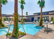 Thumbnail 36 of 68 - a swimming pool with palm trees and a building in the background at Grandstone at Sunrise, Peoria, Arizona