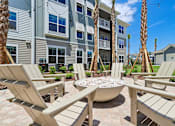 Thumbnail 108 of 124 - Fire pit seating area with adirondack chairs and palm trees at Velara Luxury Apartments, Ponte Vedra Beach, 32081