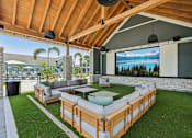 Thumbnail 8 of 62 - A wooden patio with a couch and a television screen.