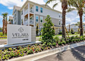 Thumbnail 88 of 124 - Property entrance sign with landscaping and palm trees at Velara Luxury Apartments, Ponte Vedra Beach