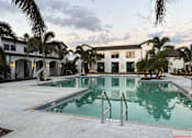 Thumbnail 9 of 17 - A swimming pool in front of a building with palm trees.