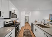 Thumbnail 14 of 45 - an open kitchen with stainless steel appliances and white cabinets at The BLVD at Wilson Crossings, Michigan