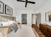 Thumbnail 17 of 20 - A bedroom with a bed, a ceiling fan, and a wooden dresser at The Levi Luxury Apartments, McDonough, GA