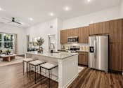 Thumbnail 11 of 57 - A modern kitchen with a white island and stainless steel appliances at The Stadler Luxury Apartments, Bradenton, FL 34210