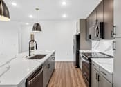 Thumbnail 21 of 24 - A modern kitchen with dark wood cabinets and white countertops.