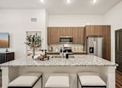 Thumbnail 21 of 57 - A modern kitchen with a granite countertop and stainless steel appliances at The Stadler Luxury Apartments, Bradenton, Florida
