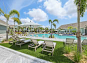 Thumbnail 4 of 62 - A poolside area with lounge chairs and palm trees.