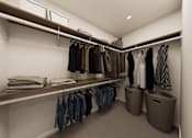 Thumbnail 35 of 48 - A walk in closet with clothes hanging and folded on shelves.