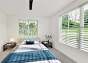 Thumbnail 22 of 32 - A bedroom with a bed, nightstands, and a window with blinds.