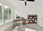 Thumbnail 17 of 32 - A room with a desk, chair, and bookshelf.