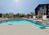 Thumbnail 31 of 32 - A swimming pool surrounded by lounge chairs and buildings.