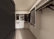 Thumbnail 33 of 35 - A walk in closet with clothes hanging and shelves.