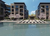 Thumbnail 48 of 48 - A swimming pool in front of a building with a row of trees in the background.