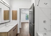 Thumbnail 33 of 124 - Bathroom with tub shower combo and wood vanity at Velara Luxury Apartments, Ponte Vedra Beach, FL