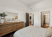 Thumbnail 23 of 57 - A bedroom with a bed, dresser, and mirror at The Stadler Luxury Apartments, Florida