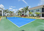 Thumbnail 14 of 62 - A tennis court is surrounded by apartment buildings.
