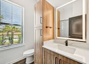 Thumbnail 20 of 43 - A bathroom with a toilet, sink, and wooden cabinet at The Hadley - North Port, FL Apartments, North Port, FL