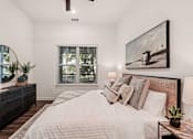 Thumbnail 12 of 57 - A bedroom with a large bed, a mirror, and a painting on the wall at The Stadler Luxury Apartments, Bradenton, FL