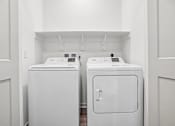 Thumbnail 10 of 24 - Two white washing machines in a small laundry room.