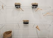 Thumbnail 17 of 57 - A white wire shelving unit with three shelves and four hangers at The Stadler Luxury Apartments, Florida 34210