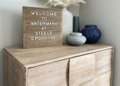 Thumbnail 42 of 56 - a wooden dresser with a vase and a sign on top of it at Watermark at Steele Crossing, Fayetteville, AR