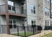 Thumbnail 87 of 88 - an apartment building with a yard and a black fence at The Depot in Raymore, MO 64083