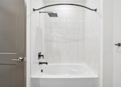 Thumbnail 21 of 39 - A white bathroom with a white tub and a white shower curtain.