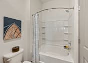 Thumbnail 36 of 60 - A white bathroom with a toilet, a bathtub, and a shower.