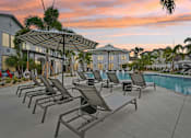 Thumbnail 4 of 43 - A poolside area with sun loungers and a building in the background. at The Hadley - North Port, FL Apartments, North Port 34287