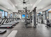 Thumbnail 13 of 24 - A spacious gym with treadmills, elliptical machines, and a weightlifting area.