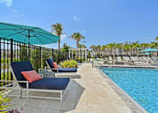 Thumbnail 67 of 68 - A pool area with chairs and a blue umbrella. at The Sophia, Venice, FL