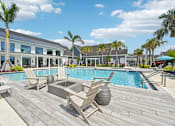Thumbnail 13 of 54 - A pool area with chairs and a palm tree.