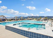 Thumbnail 15 of 24 - A large outdoor swimming pool with a blue tiled edge and a white tile edge.