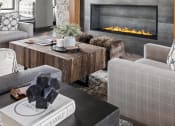 Thumbnail 11 of 46 - a living room with a stone fireplace and a tv above it at Alta25, Monument, CO, 80132