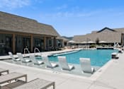 Thumbnail 8 of 46 - A pool with chairs and a building in the background.