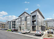 Thumbnail 55 of 59 - an apartment building with cars parked in a parking lot at The Quarry Luxury Apartment Homes, Fort Collins, CO