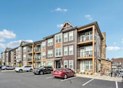 Thumbnail 54 of 59 - an apartment building with cars parked in front of it at The Quarry Luxury Apartment Homes, Fort Collins, CO