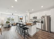 Thumbnail 7 of 59 - an open kitchen and living room with a stainless steel refrigerator at The Quarry Luxury Apartment Homes, Fort Collins, CO